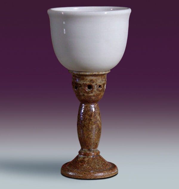 A white cup sitting on top of a wooden pedestal.